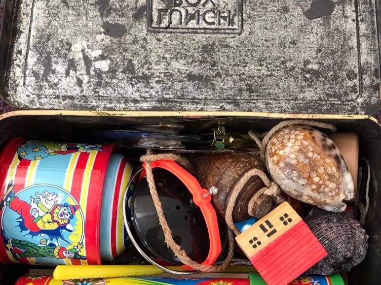 Old metal lunchbox containing shells, a gyroscope and old toys